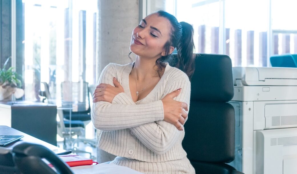 a woman sitting at a desk with her arms crossed