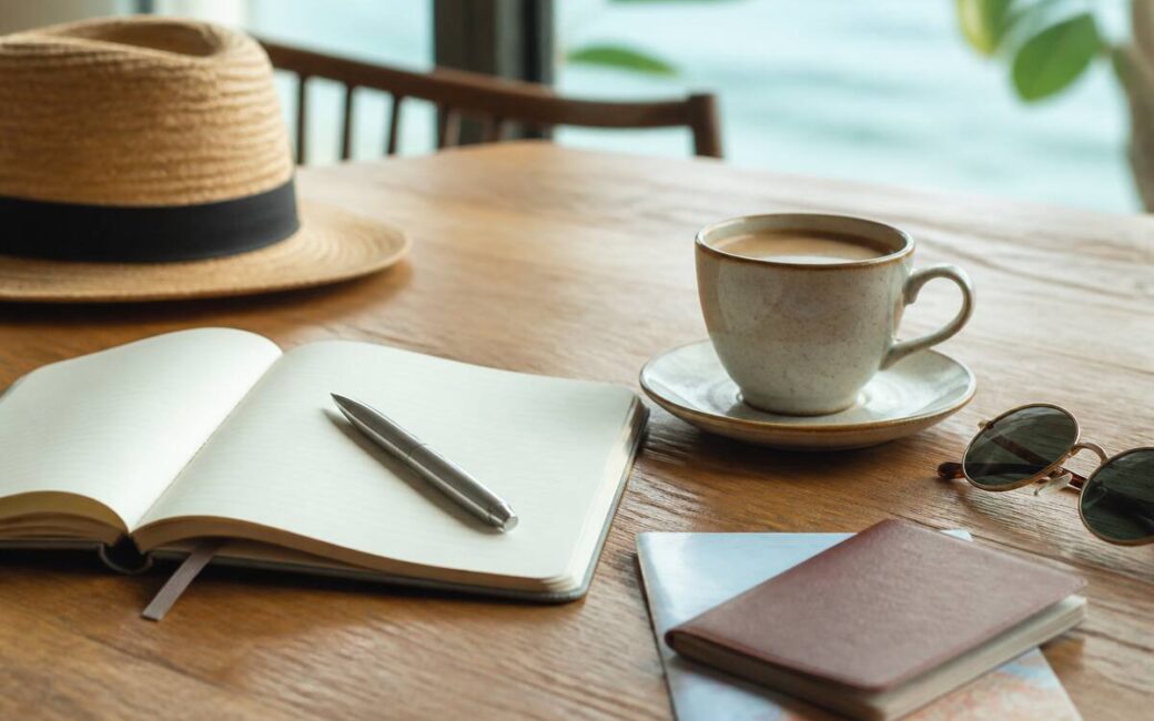 Notitieboek en reisbenodigdheden op tafel tijdens het plannen van een rustige vakantie
